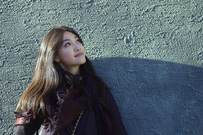 Young woman standing against wall