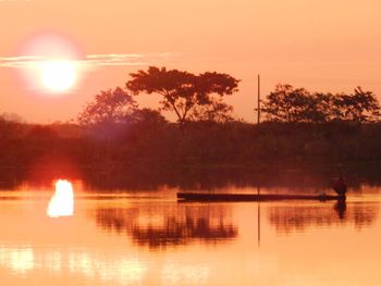 Silhouette trees by lake against sky during sunset