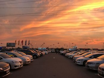 Cars on city street against sky during sunset