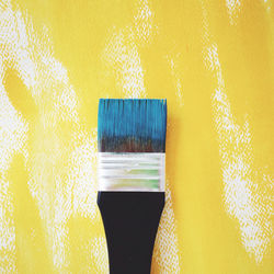 High angle view of paintbrush on yellow fabric