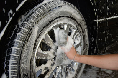Close-up of man cleaning car with soap