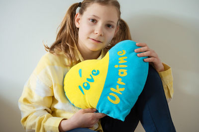 Portrait of smiling young woman standing against wall