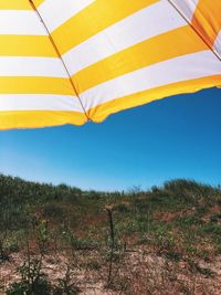 Low angle view of multi colored umbrella against blue sky