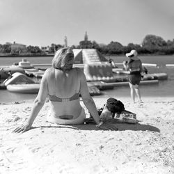 Rear view of woman on beach against sky