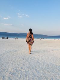 Full length of woman standing on beach against sky