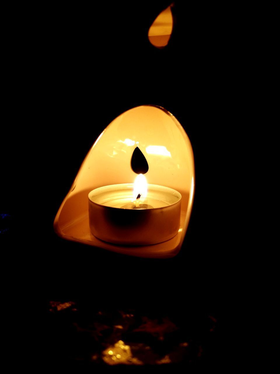 CLOSE-UP OF LIT CANDLE IN DARK