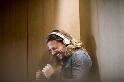 Portrait of excited man listening music with headphones