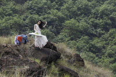 Woman ironing clothes in forest