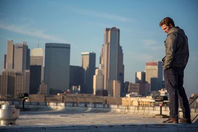 Man standing against modern buildings in city