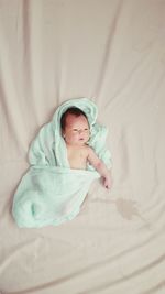 Directly above shot of newborn baby lying on bed