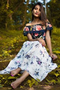 Beautiful young woman sitting on land