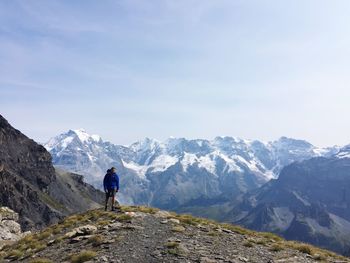 Rear view of man walking on mountain against sky