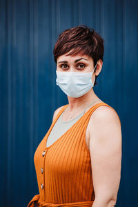 Portrait of young woman standing against blue wall