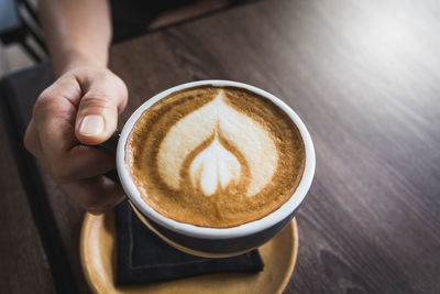 Midsection of woman holding coffee cup on table