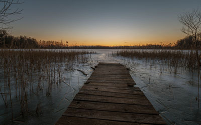 Pier over lake against sky during sunset