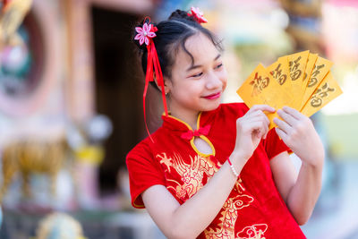 Happy girl holding red umbrella against blurred background