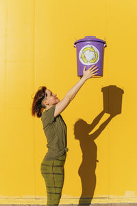 Full length of a woman holding yellow wall