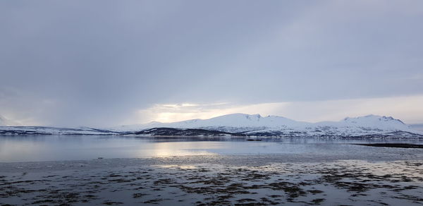 Scenic view of lake by snowcapped mountains against sky during winter