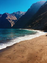 Scenic view of sea and mountains against blue sky