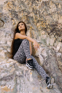 Low angle view of young woman sitting on rock