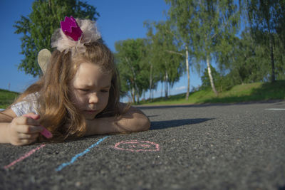 Portrait of girl with umbrella on road against trees