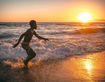 Woman on beach against sky during sunset