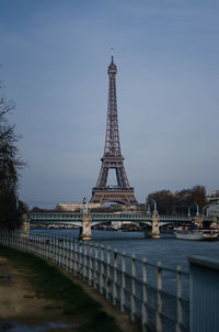 Low angle view of eiffel tower over river against sky at dusk