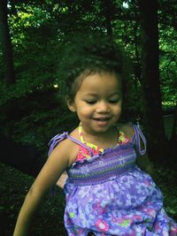 Cute girl looking away while sitting on tree at park