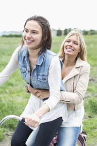 Happy female friends enjoying bicycle ride on country road