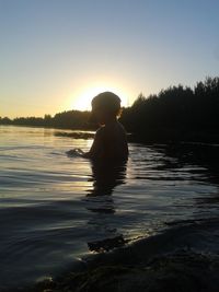 Rear view of silhouette people in lake during sunset