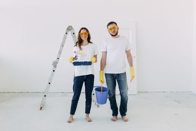 Happy smiling married couple engaged in renovation repair in the room of the house preparing to move