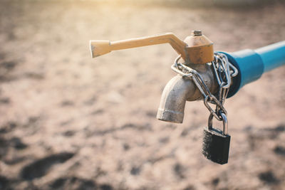 Close-up of padlock hanging on faucet outdoors