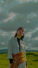 An indonesian girl wears a typical traditional woven cloth stand against the sky.