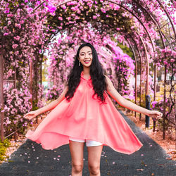 Portrait of beautiful woman standing by pink flower