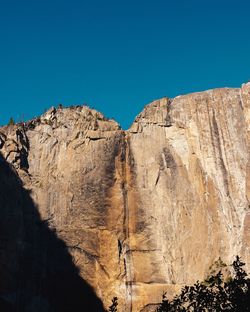 Low angle view of rocks against blue sky