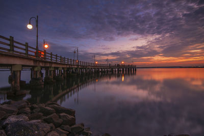 Illuminated bridge against sky during sunset