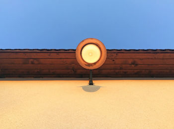 Low angle view of illuminated lamp against wall