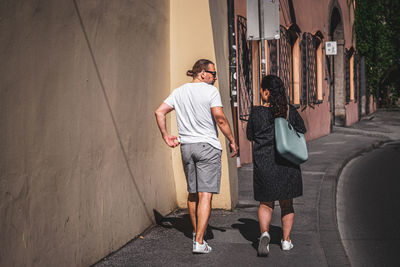 Rear view of friends standing on street in city