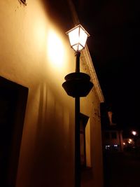 Low angle view of illuminated street light against building