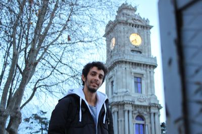 Portrait of young man standing against building