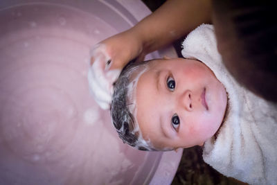 Cropped hand bathing baby in tub