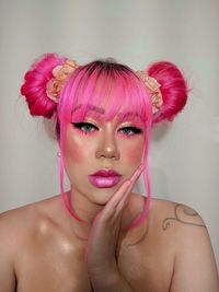 Portrait of beautiful young woman against pink background