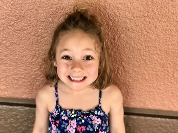 Portrait of smiling cute girl against wall