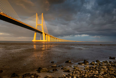 Vasco da gama bridge at sunset with dramatic cloudy blue sky in lisbon, portugal