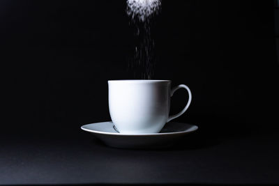 Close-up of coffee cup on table against black background