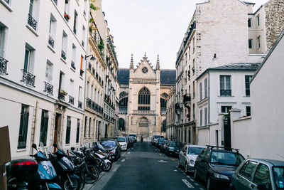 Cars on road amidst buildings in city against sky