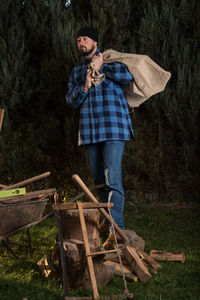 Lumberjack holding jute bag against trees at forest