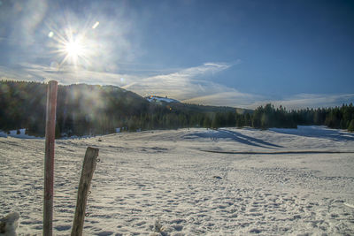 Scenic view of snow covered field against bright sun