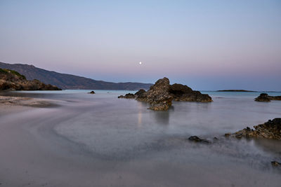 Rocks on beach against clear sky