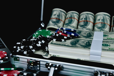 Close-up of gambling chips and paper currencies on suitcase